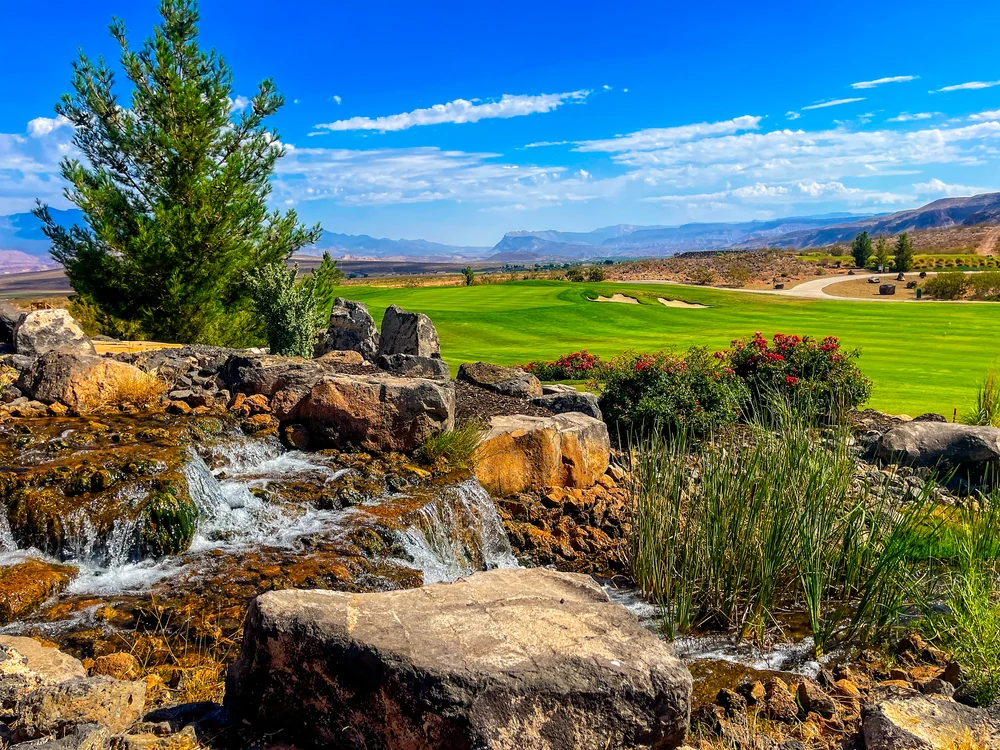 Water flowing over rocks beside trees and a golf fairway at Copper Rock.