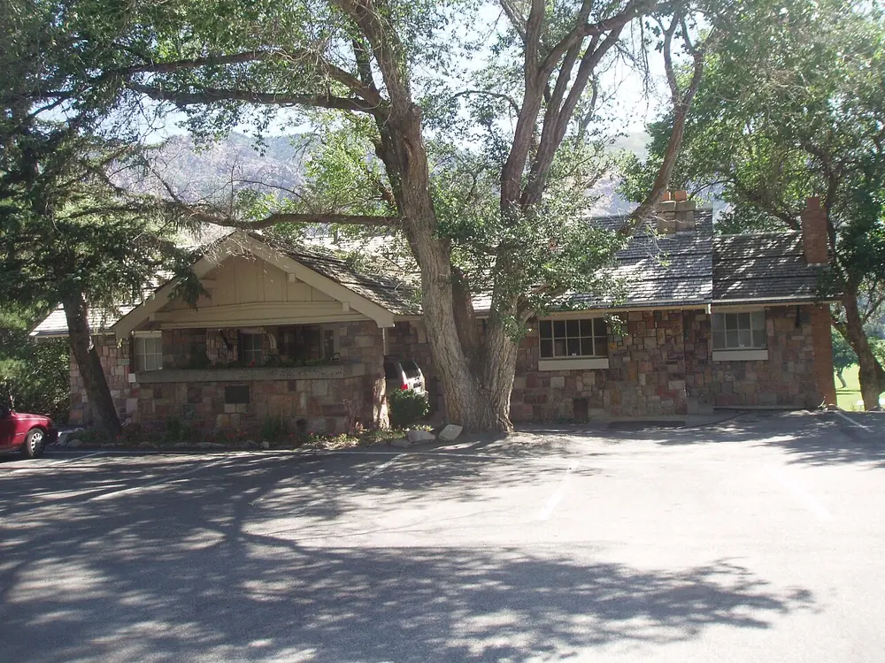 The stone El Monte clubhouse beneath trees in Ogden