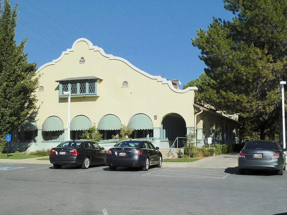 The pale stucco historic clubhouse at Forest Dale, with arched windows and parked cars