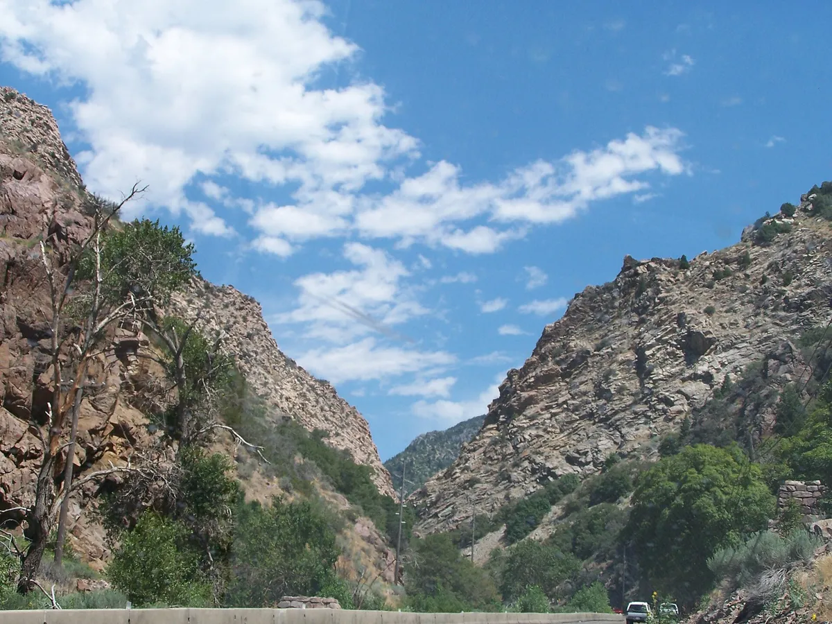 Steep rocky walls of Ogden Canyon rising above the highway on a summer day