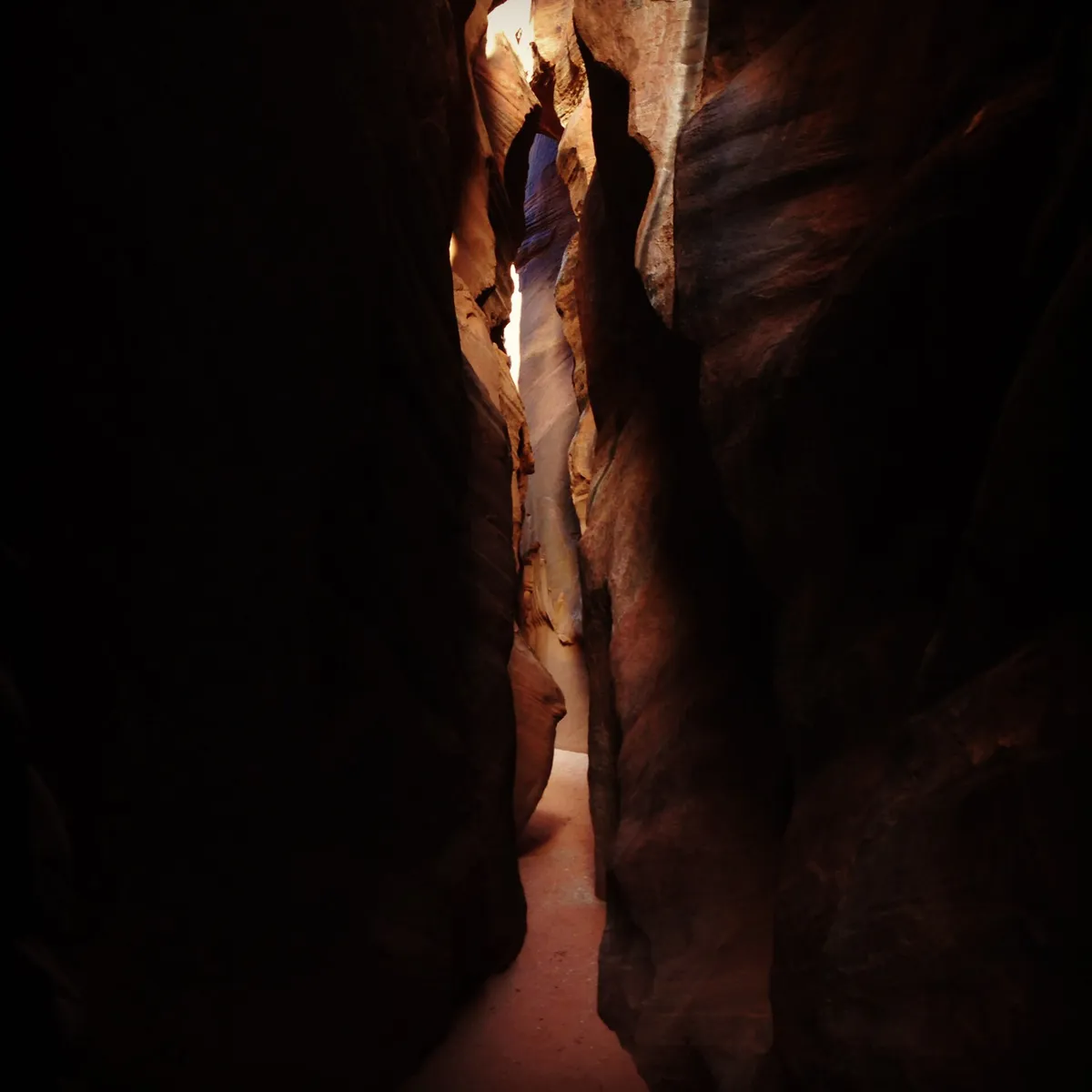 A narrow sandstone slot canyon in Wire Pass with a sliver of light overhead