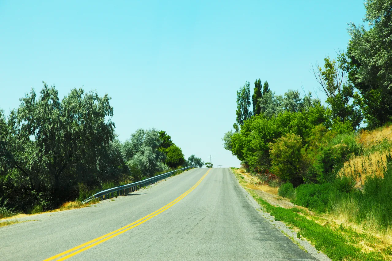 An empty rural Utah road bordered by trees, photographed in 2013