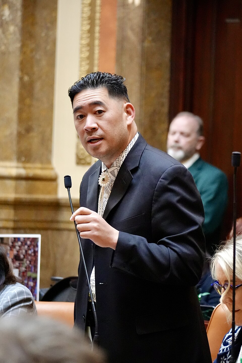 Jake Fitisemanu speaking into a microphone in the House chamber.