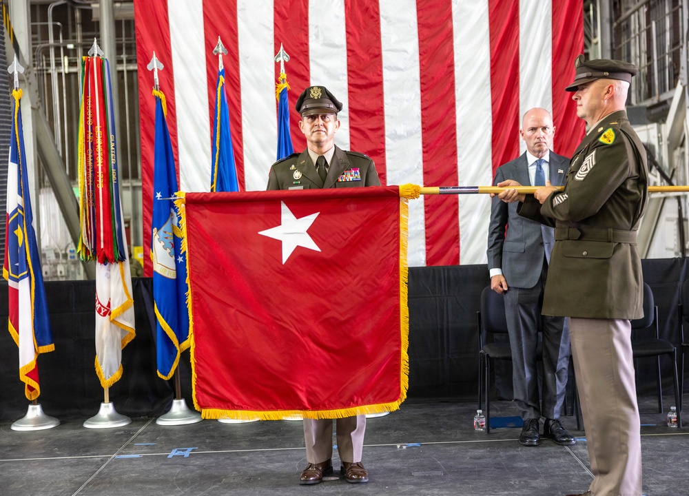 Michael Kjar, left, stands behind a red one-star flag while Spencer Cox stands behind the flag at right during the August 3, 2026 command ceremony.