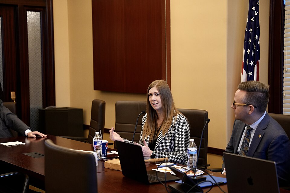 Stephanie Gricius speaking at a conference table with other attendees.