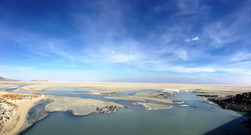 Water channels and exposed shoreline at the southern end of the Great Salt Lake beneath a blue sky