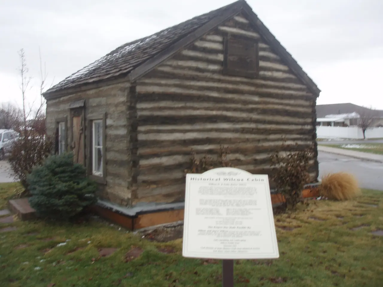 The Daughters of Utah Pioneers museum in Syracuse, a small log building with a plaque