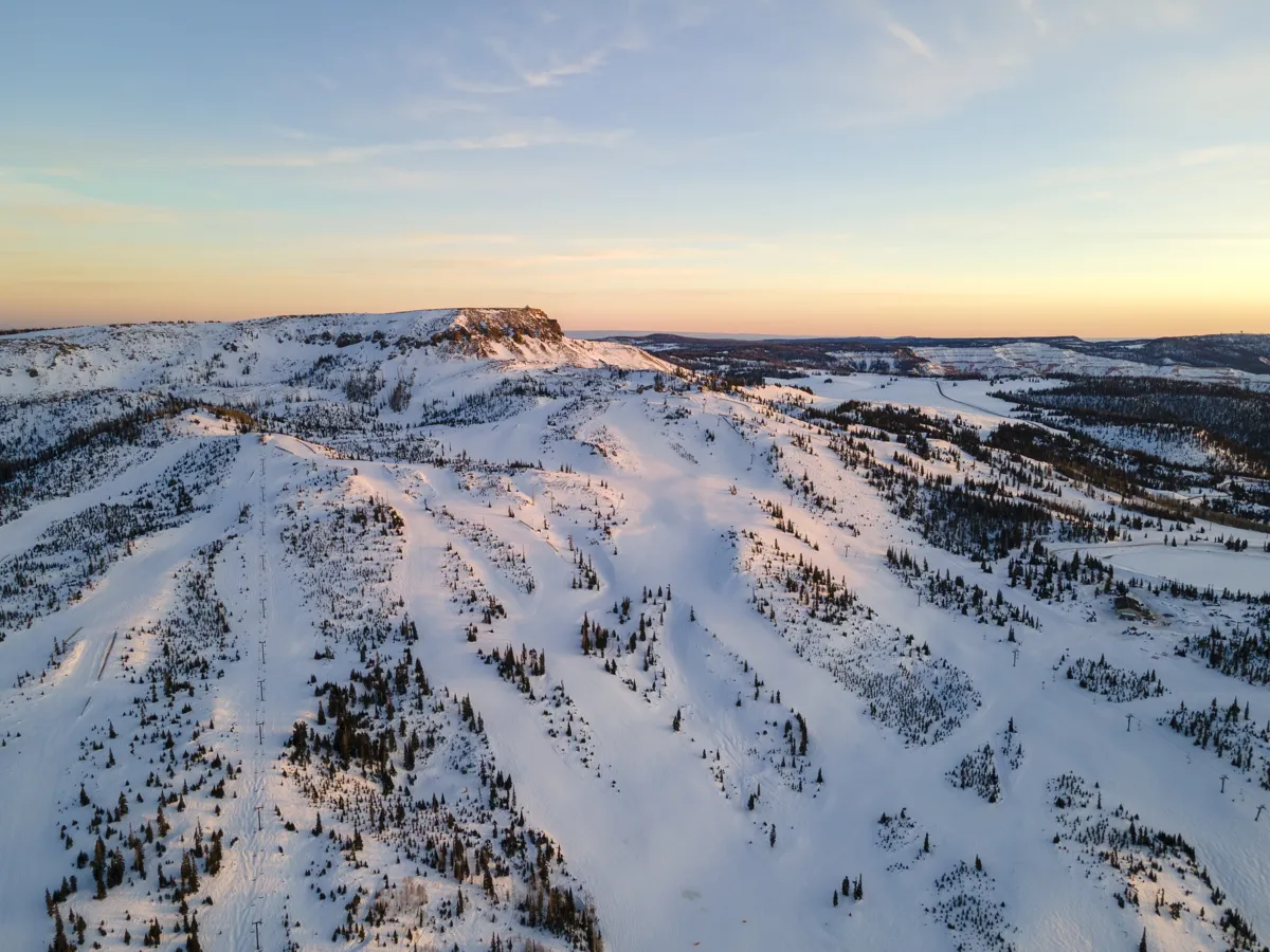 Snow-covered slopes and Brian Head Peak beneath a pale sunset sky.